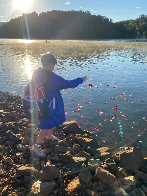 Throwing rose petals in the lake in memory of loved ones taken by cancer during the 2022 Swim Across America